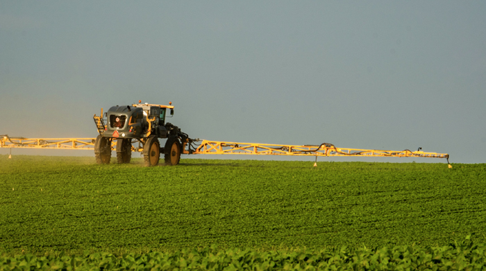 A spray tractor in driving through on a farm