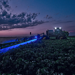 Sprayer spraying a farm at night